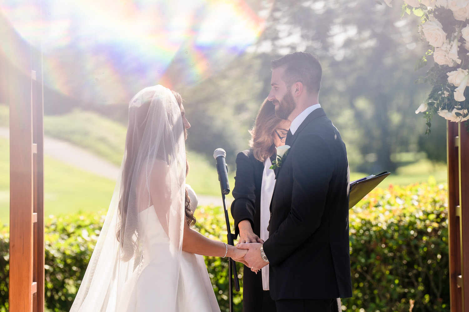 Intimate moment of the couple holding hands during their wedding vows.