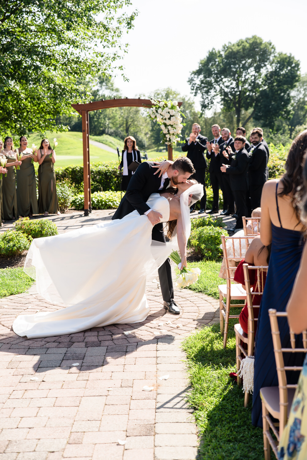 Bride and groom kissing under a wooden arch during their outdoor ceremony.