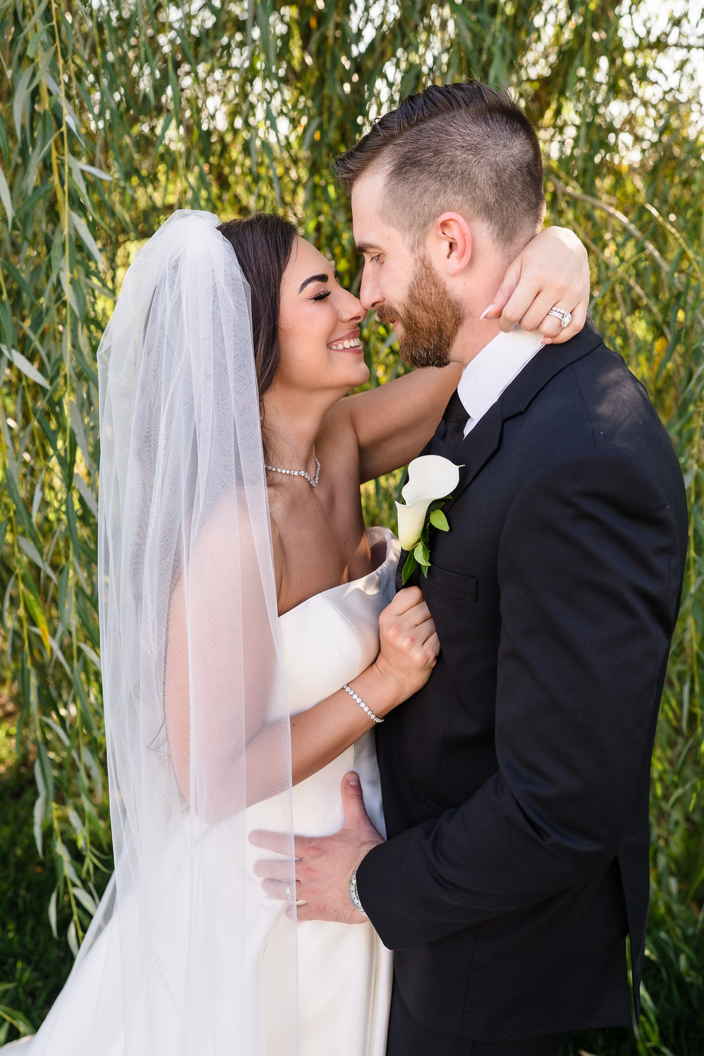 Portrait of the bride and groom sharing a moment under a willow tree.