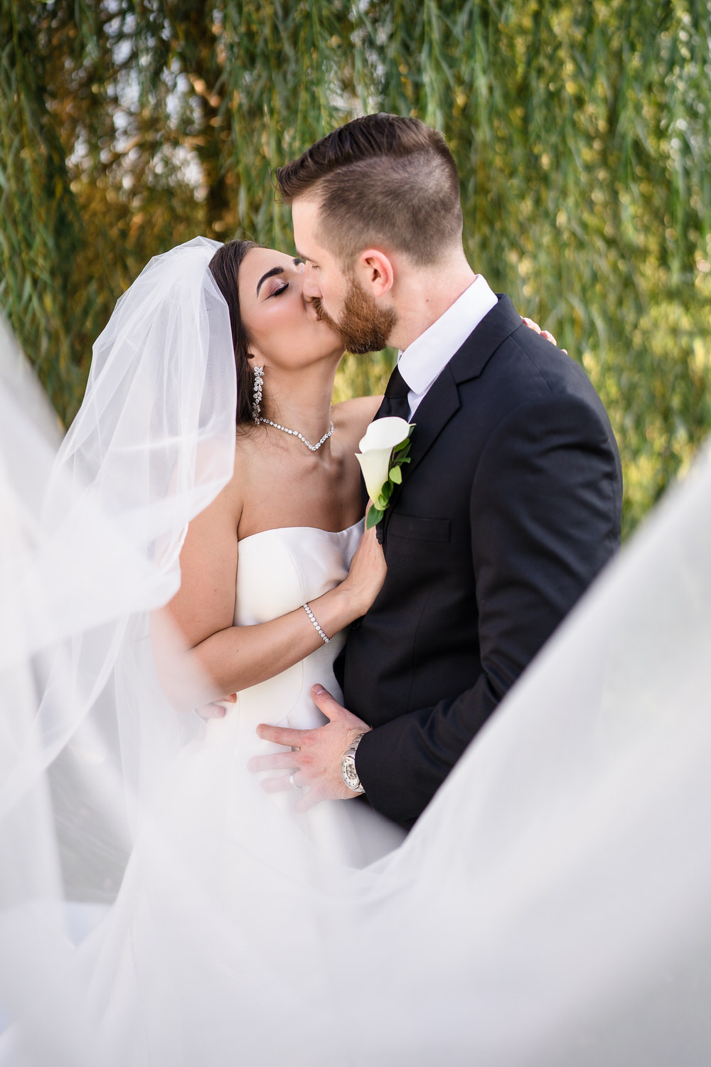 Romantic portrait of the bride and groom kissing under the bride's flowing veil.