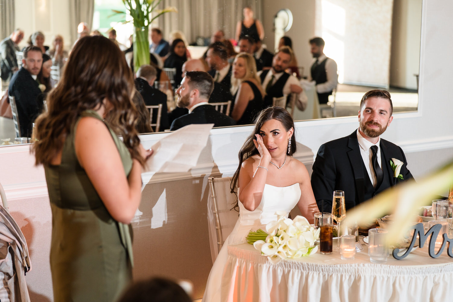 Emotional moment of the bride listening to a toast during the reception.