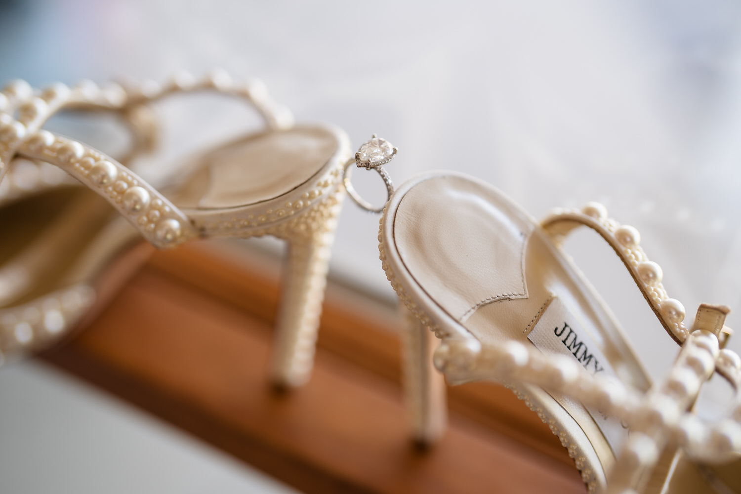 Detail of the bride’s wedding shoes and jewelry set against a warm background.