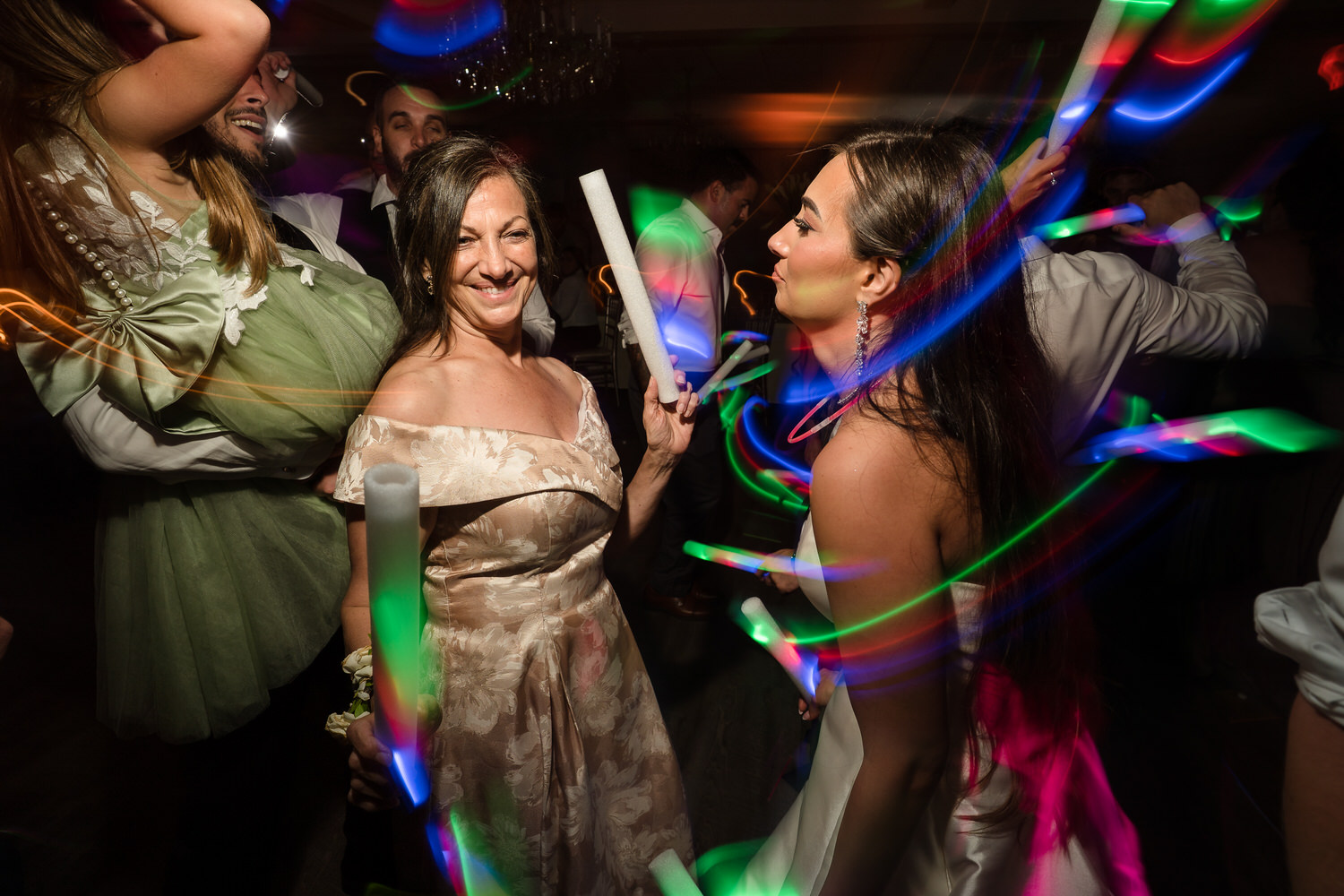 Reception guests in formal wear dancing with glow sticks at The Club at Twin Lakes.