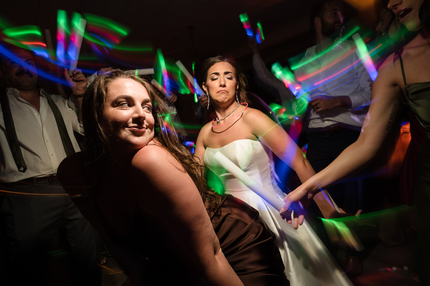 Guests on the dance floor using colorful LED glow sticks during a high-energy party.