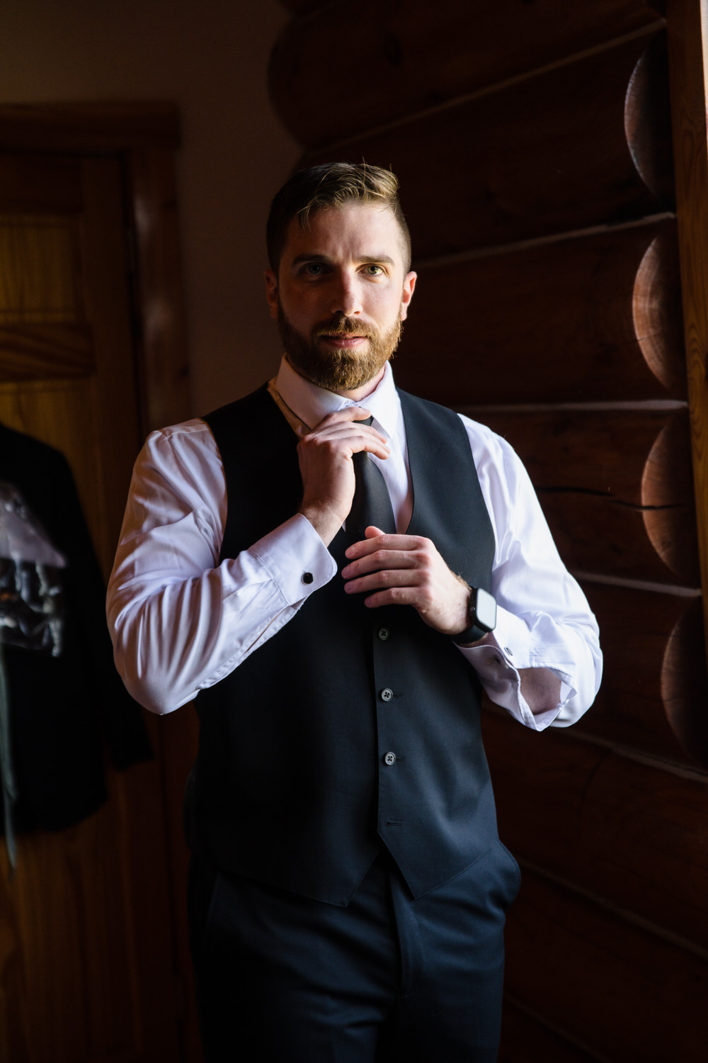 Groom adjusting his tie in a mirror before the ceremony.