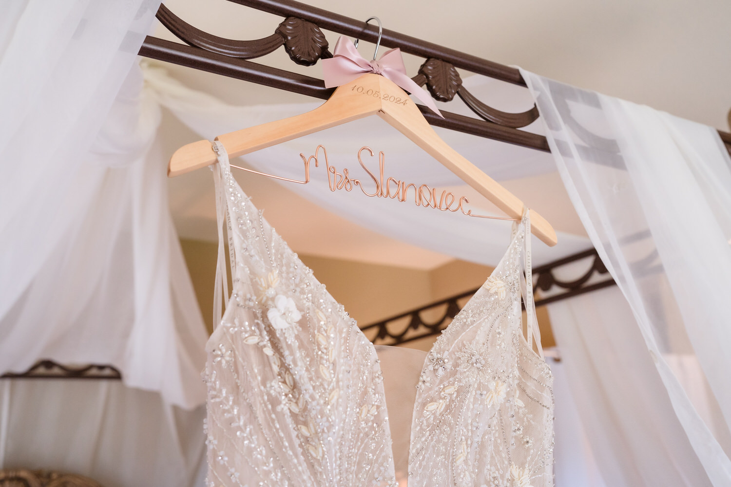 Close-up detail of the wedding dress hanging on a custom wooden hanger at the Woodstone Lodge.
