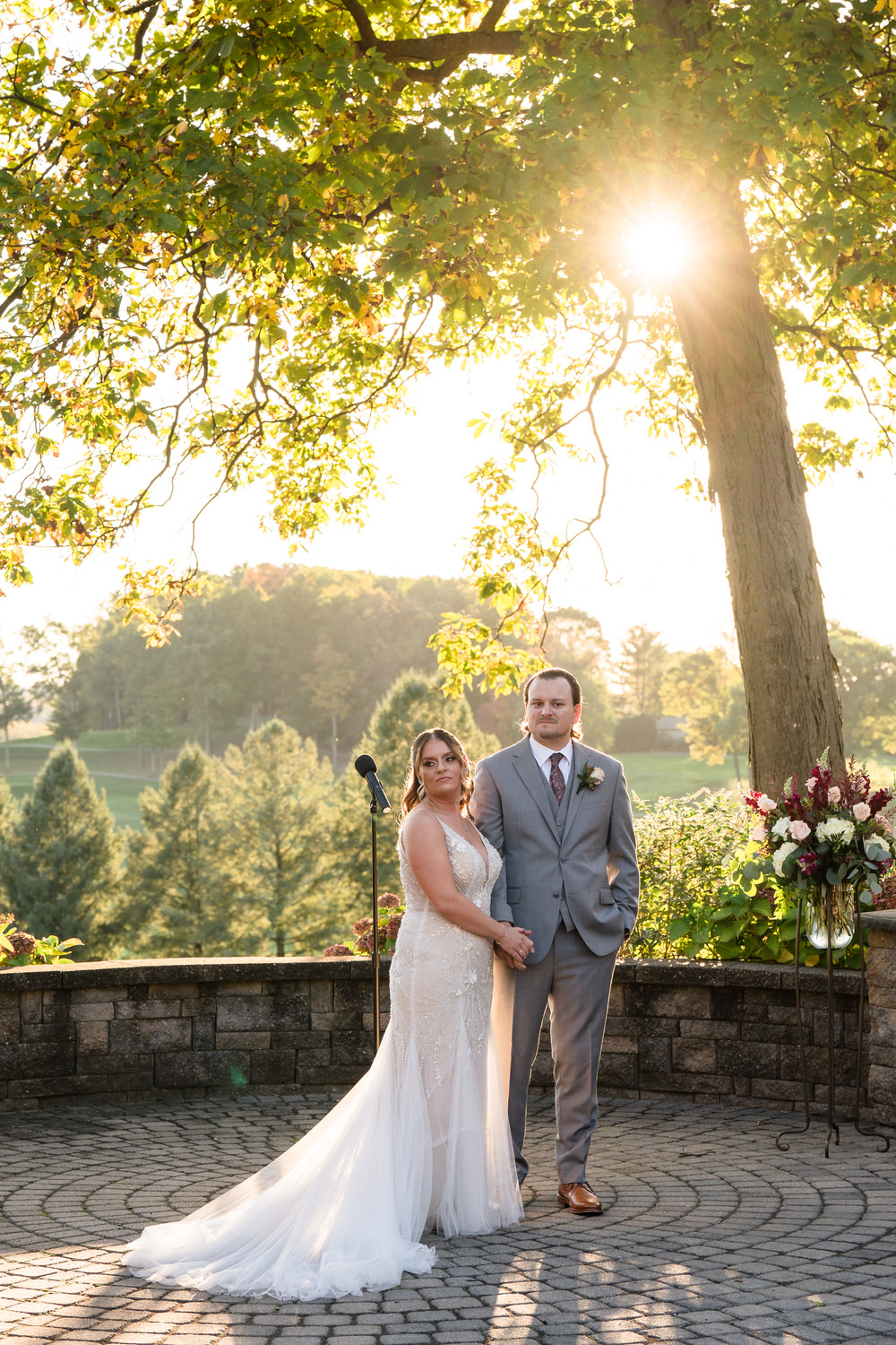 Sun-drenched portrait of a bride and groom standing in the open fields of the Woodstone Country Club estate.