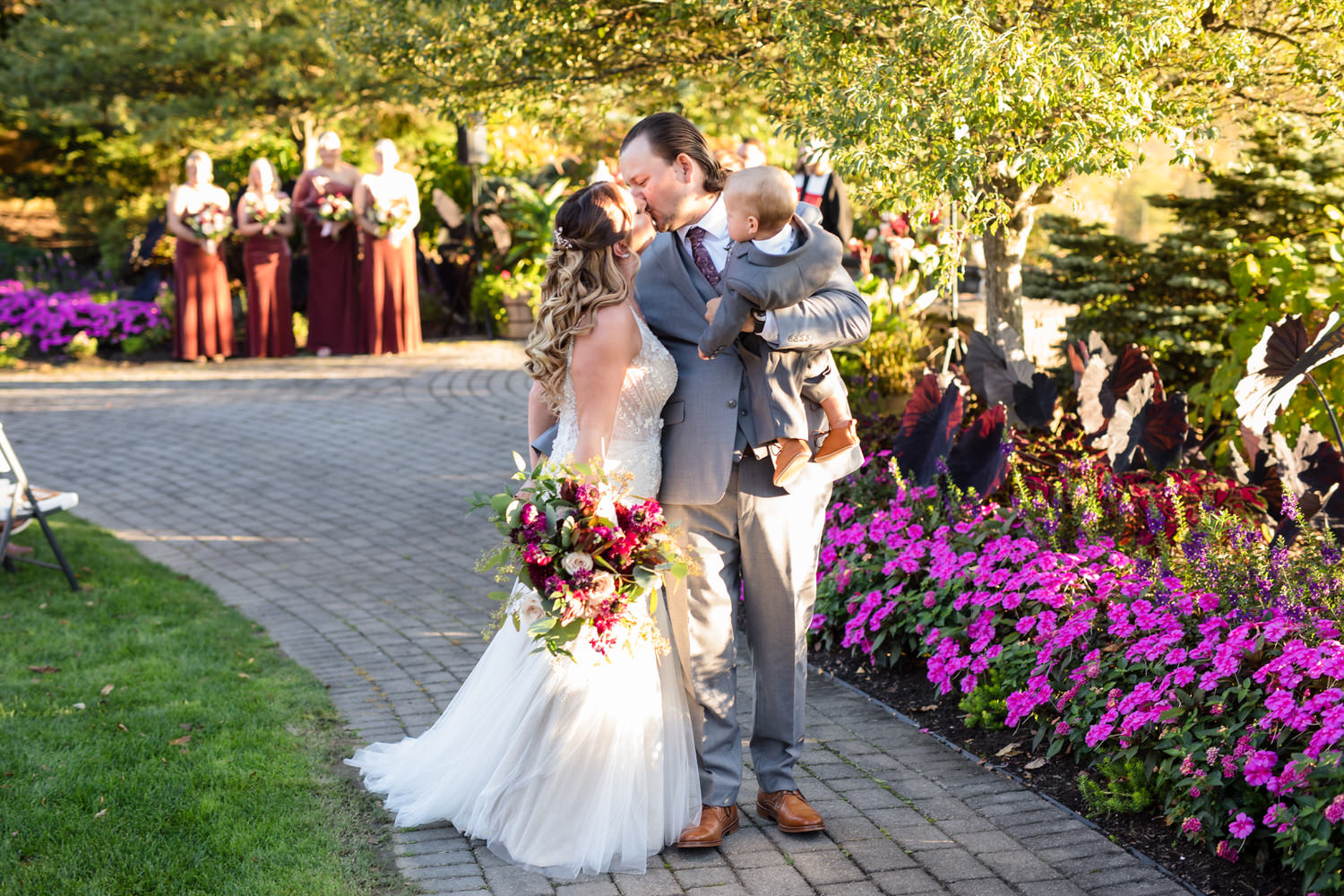 Natural light portrait of a bride and groom walking through the lush, vibrant florals of the Woodstone ceremony site.
