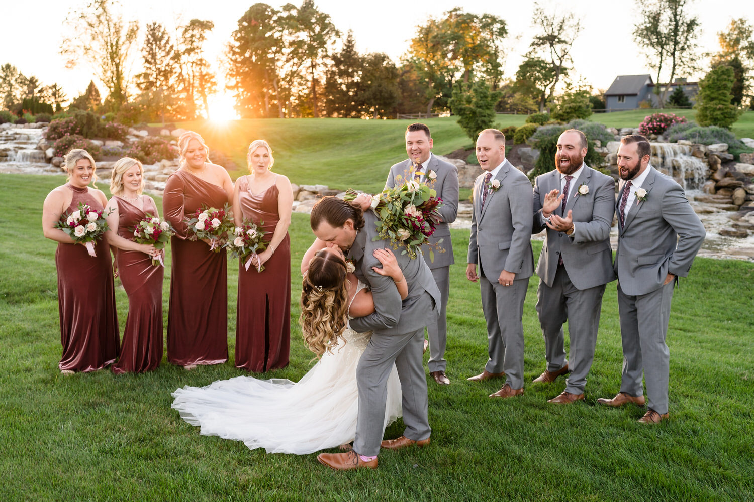Vibrant group portrait of the bridal party laughing together in the flower-lined gardens of the Woodstone estate.