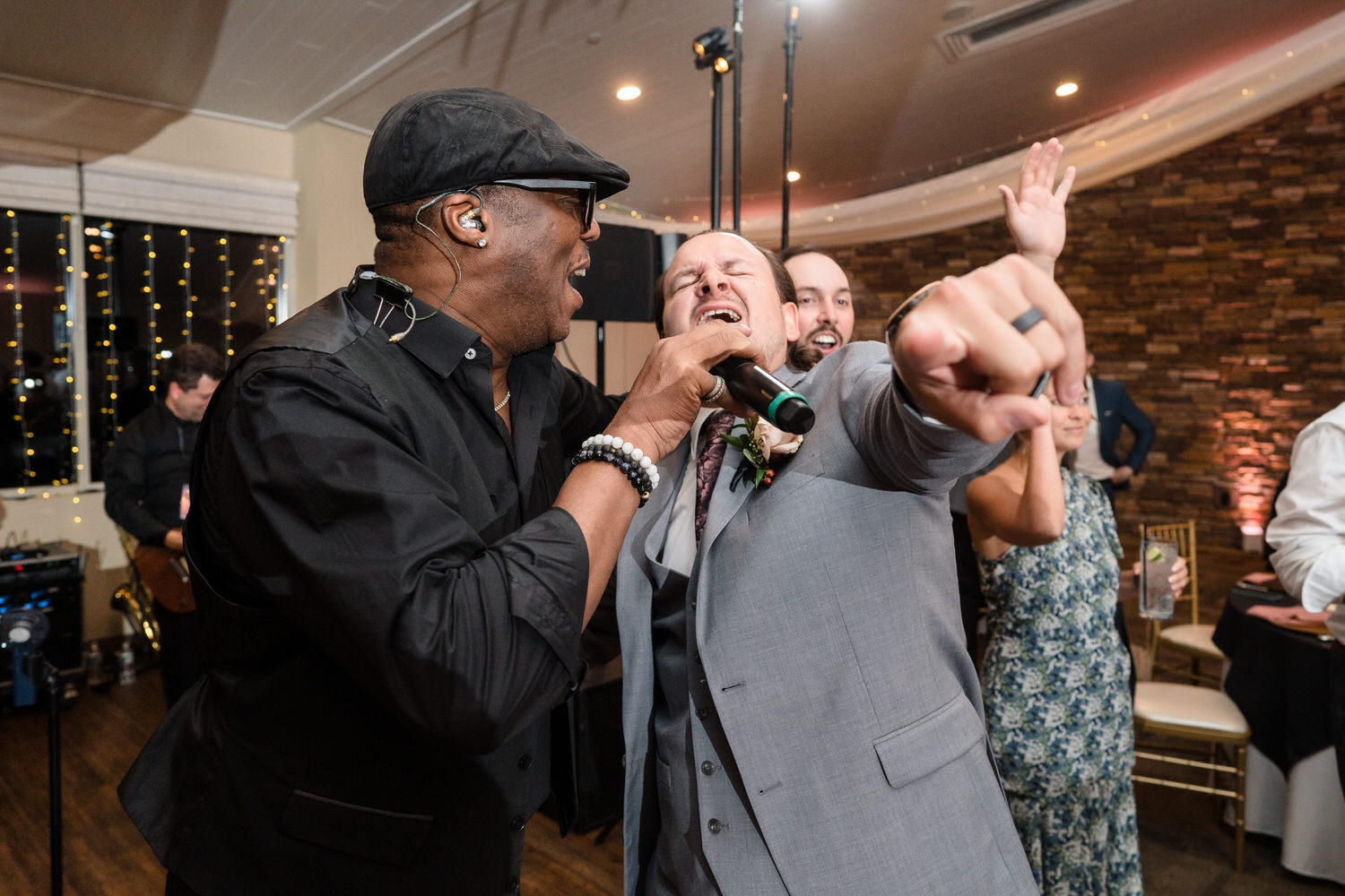 Vibrant reception candid of guests and the groom laughing and singing together during a high-vibe party.
