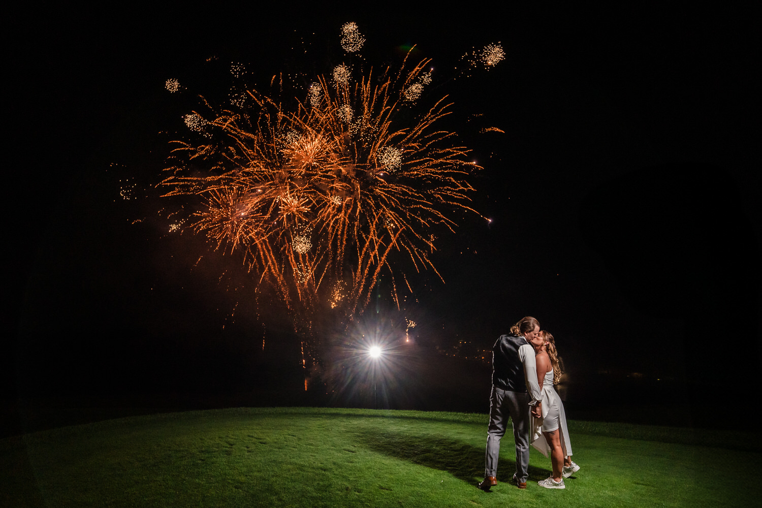 Night wedding portrait of a couple kissing under a grand fireworks display at Woodstone Country Club in Danielsville, PA.