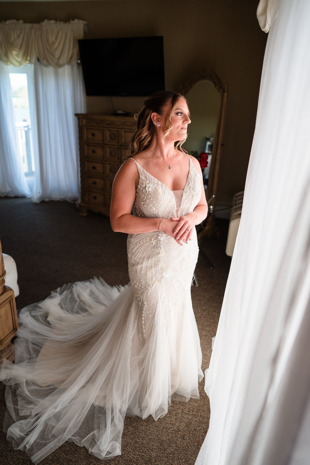 Morning-of portrait of a bride looking out the window of the Woodstone Lodge getting-ready suite.