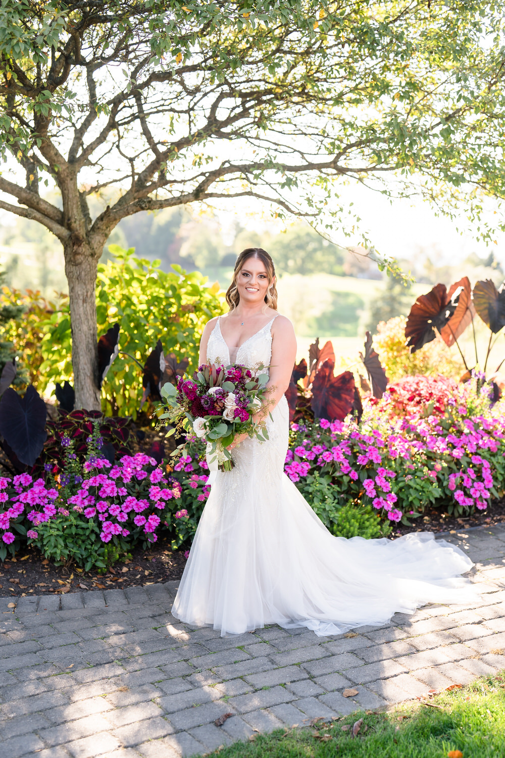 Vibrant, flower-framed portrait of a bride standing in the Woodstone Gardens during the peak of spring blooms.