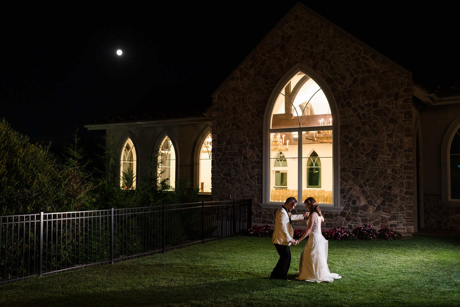 bride and groom dancing under moonlight in front of the park savoy chapel