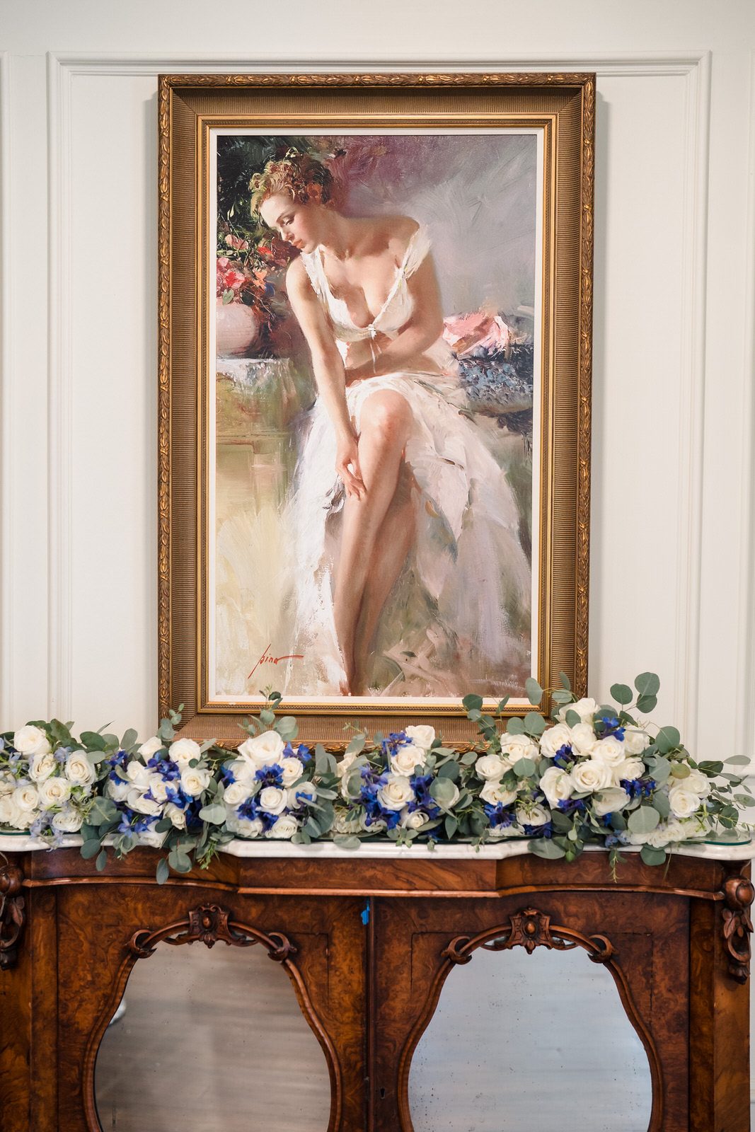 wedding flowers on a mantle in front of a painting