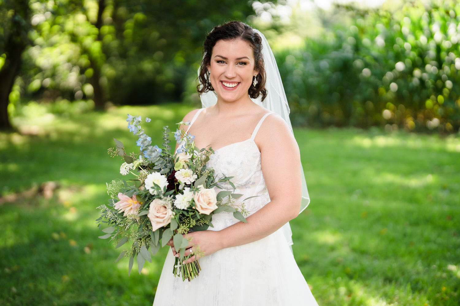 Full-length bridal portrait of Olivia posing in her white gown in a green field.