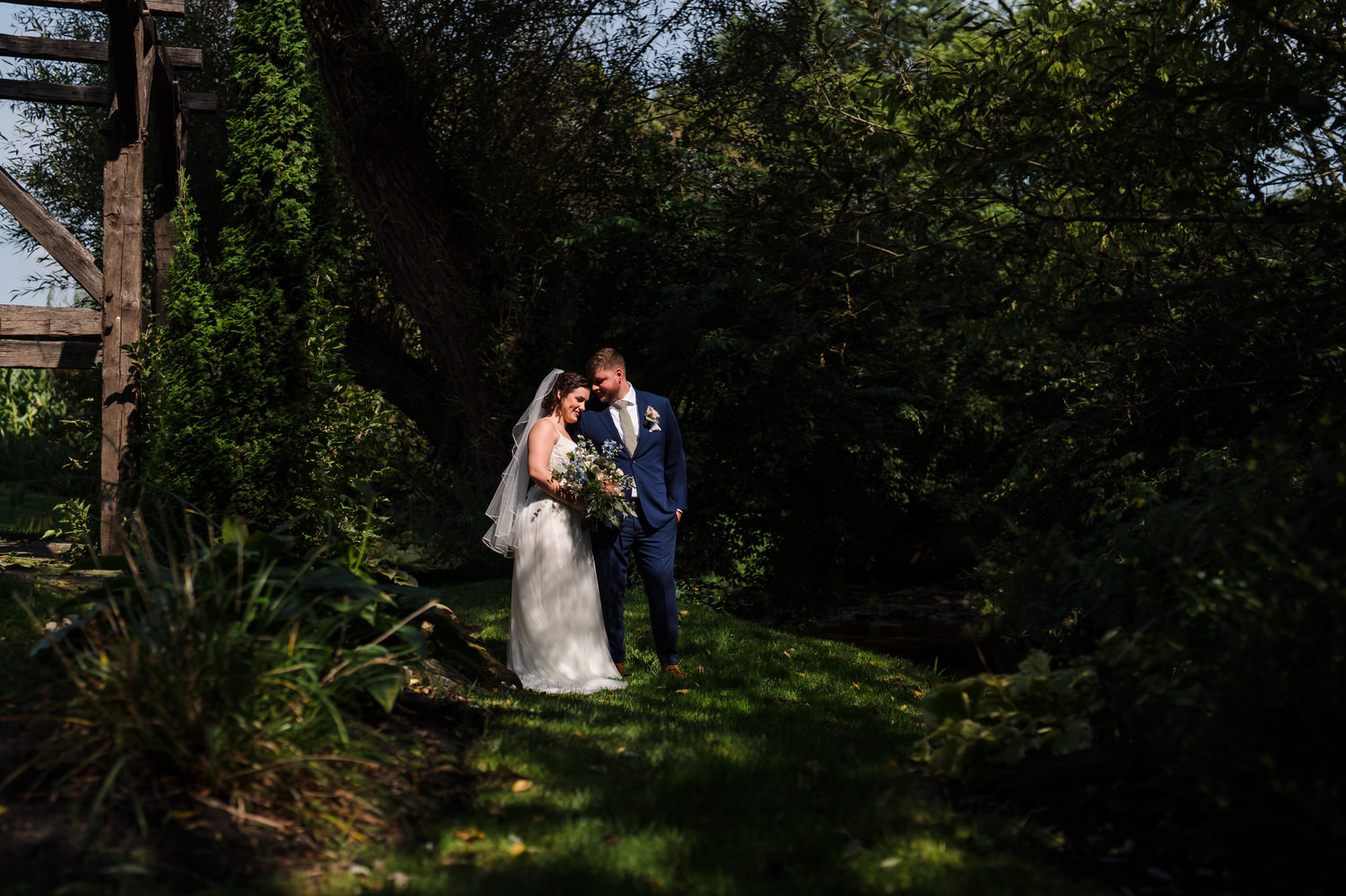 Bride and groom sharing a quiet moment together in a shaded forest setting.