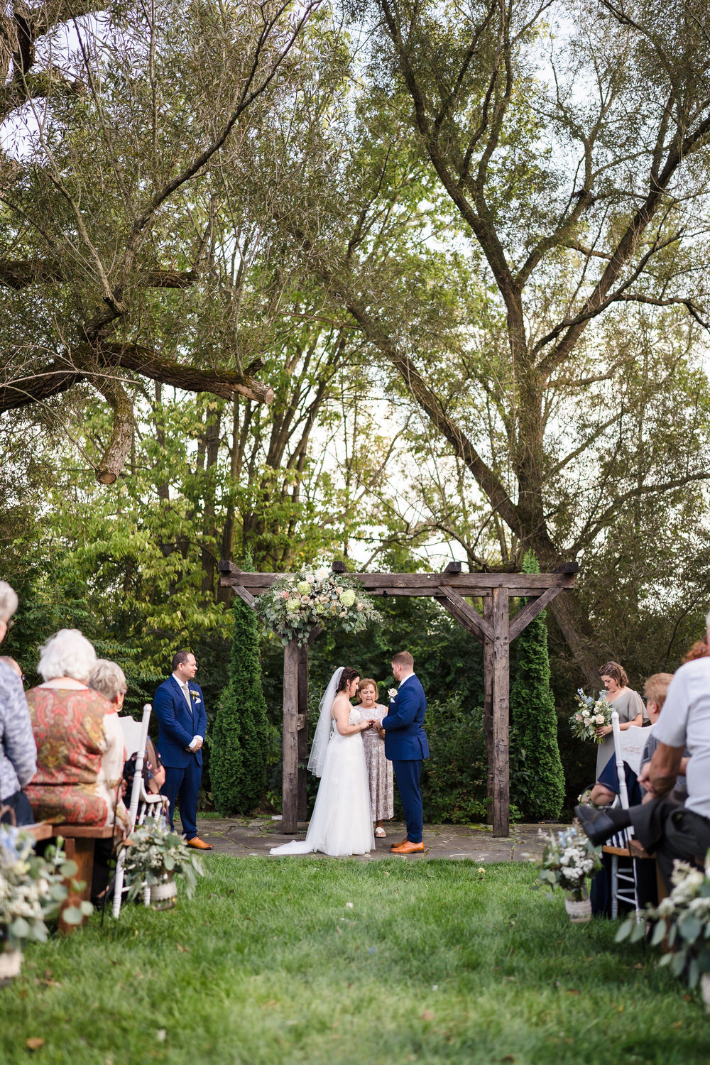 Wide shot of the outdoor ceremony at Barn Swallow Farm under mature trees.