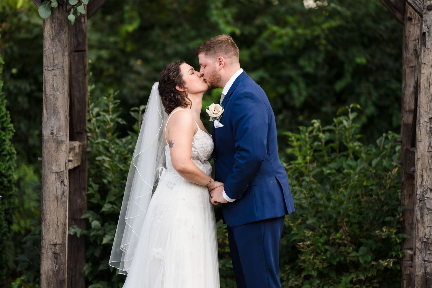 Romantic portrait of the bride and groom kissing in a lush green garden.