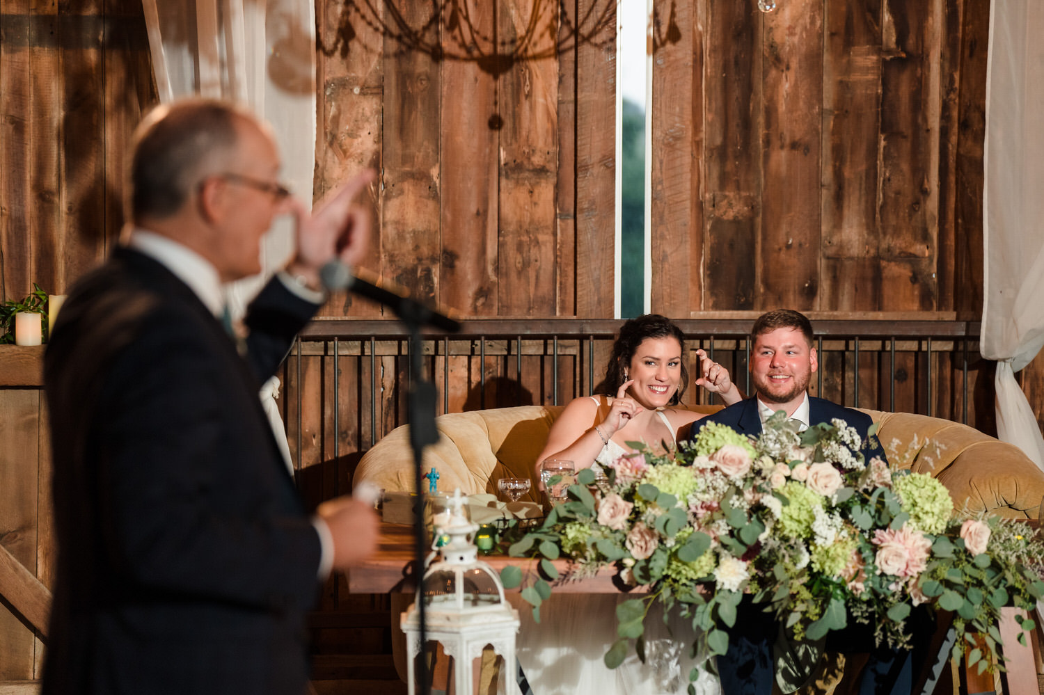 photograph of the father of the bride giving a speech with his daughter and son in law watching