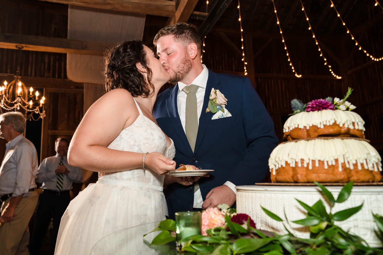 Bride and groom sharing a kiss while cutting their wedding cake.