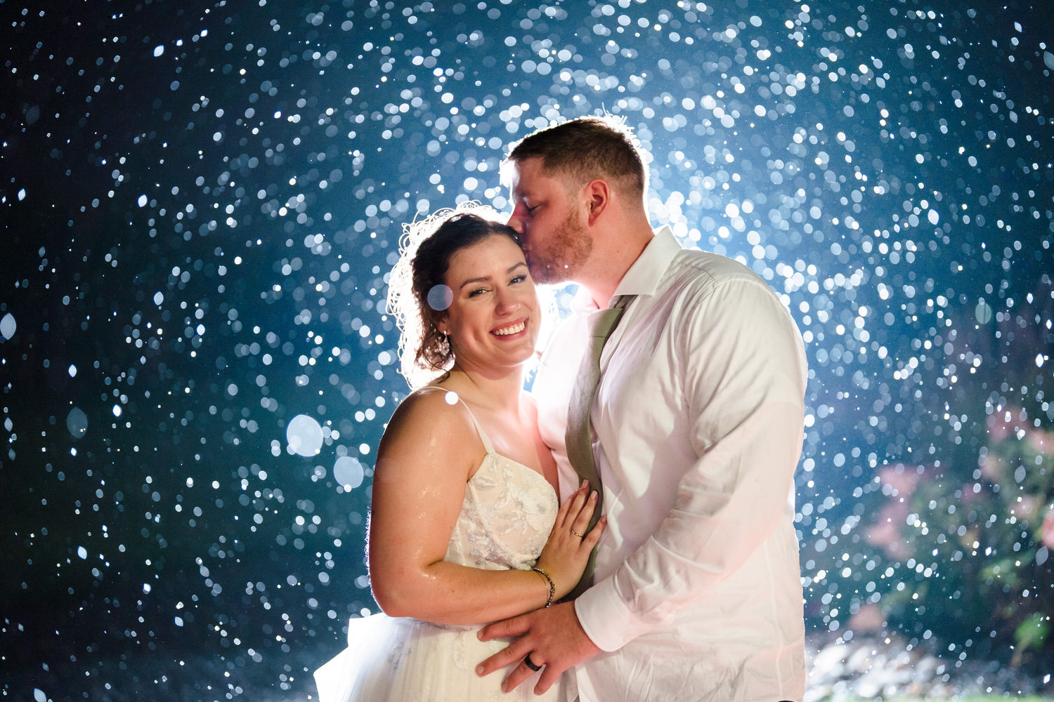 Phenomenal backlit night portrait of the bride and groom in the rain.