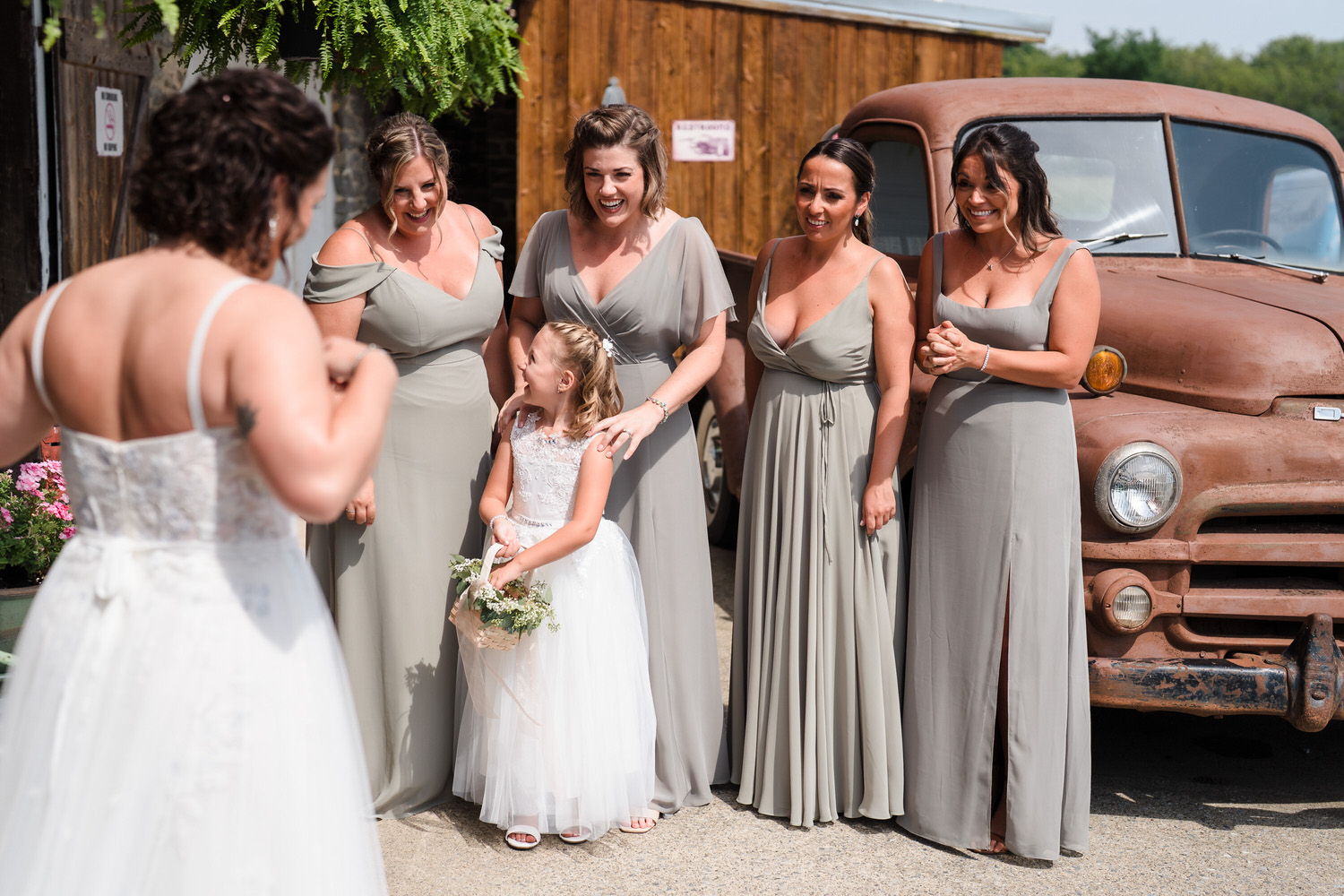 Candid of the bride and bridesmaids laughing together outside the barn.