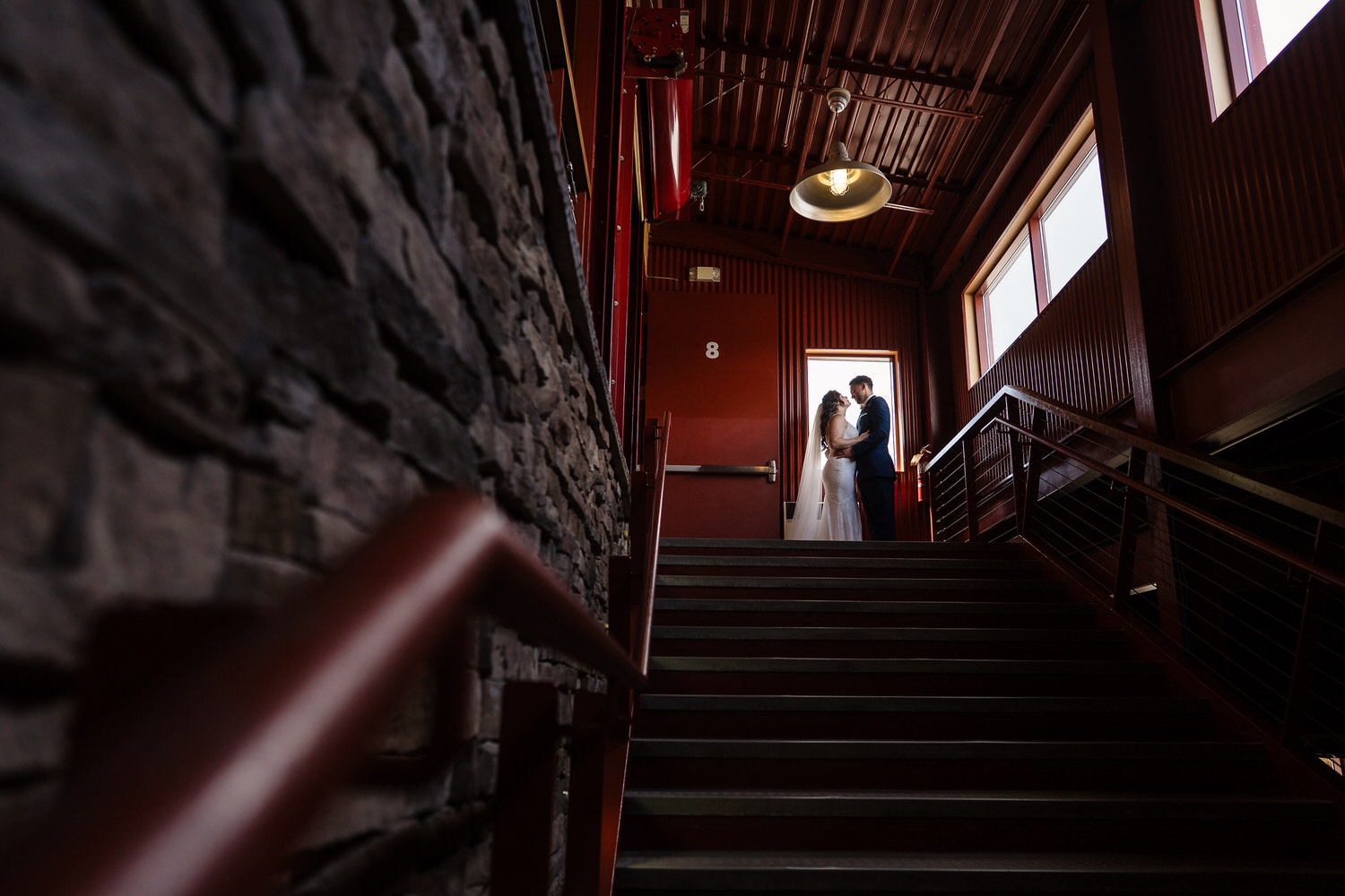 Bride and Groom Inside Bear Creek Mountain Resort on their wedding day for a couple's portrait on the staircase by a window.