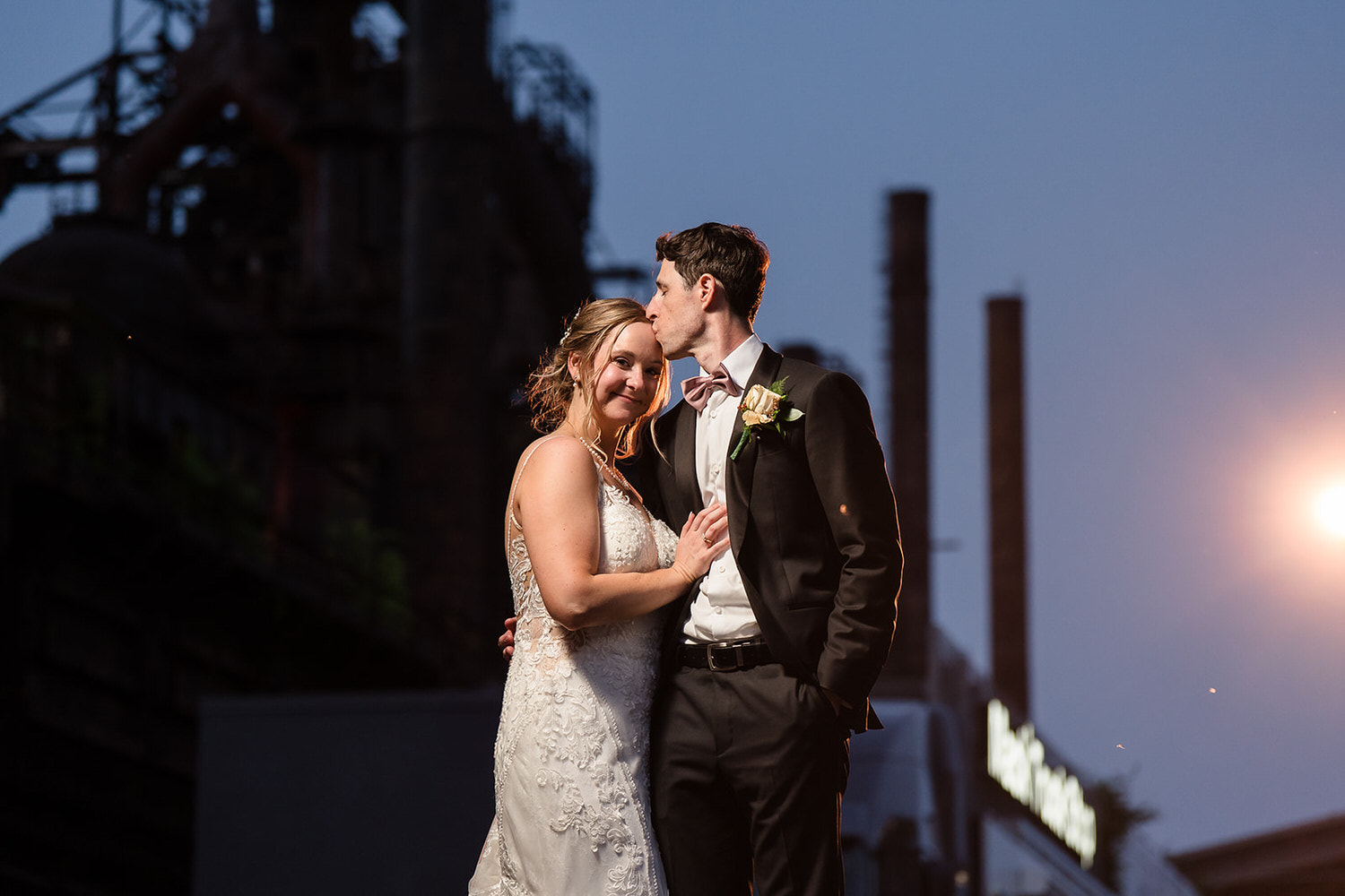 Romantic night portrait of a bride and groom in front of the illuminated industrial ruins at Steel Stacks in Bethlehem, PA.