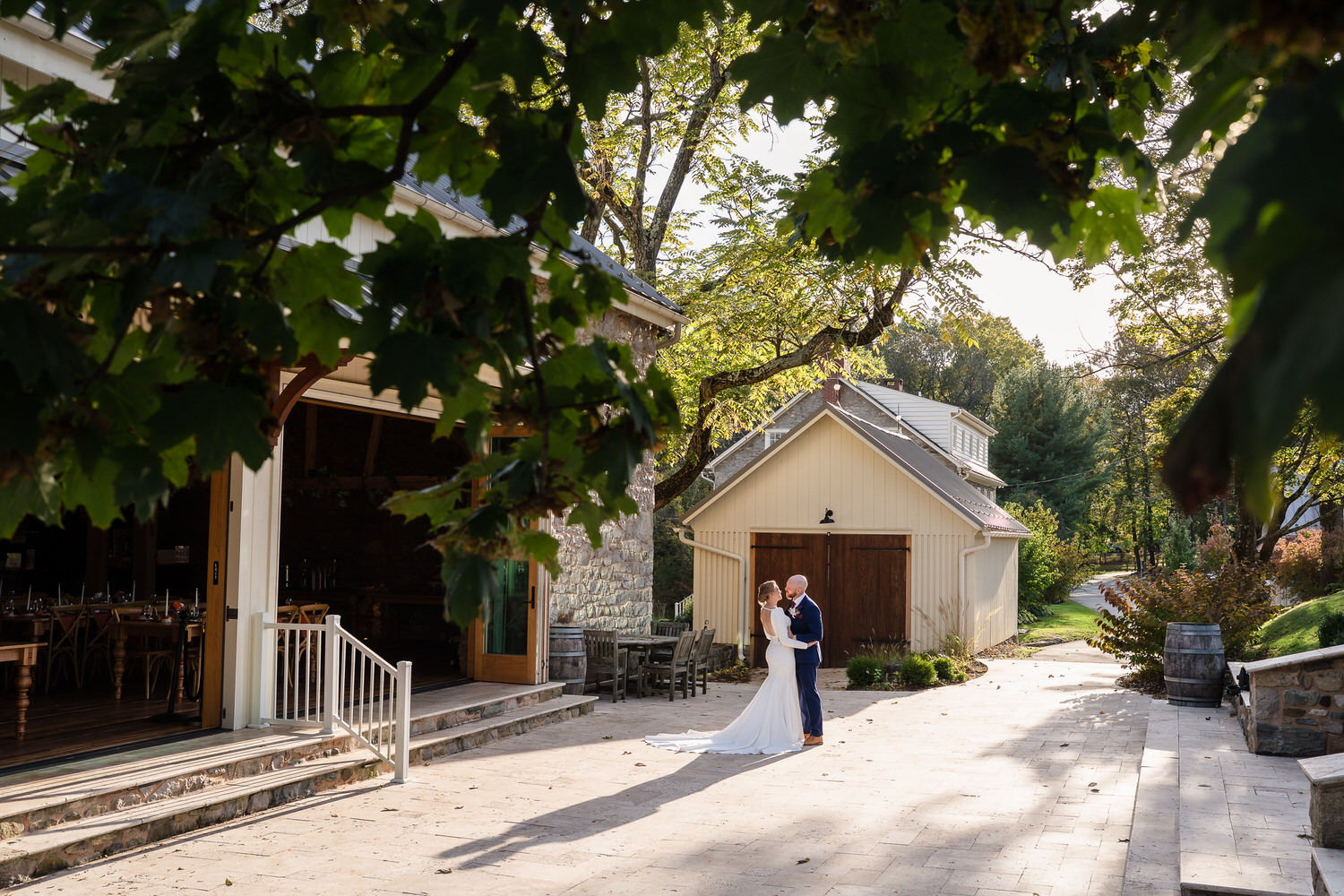 Newlyweds embracing on the stone patio outside the historic Grand Barnroom at Domaine Pterion winery in Macungie, Lehigh Valley PA.