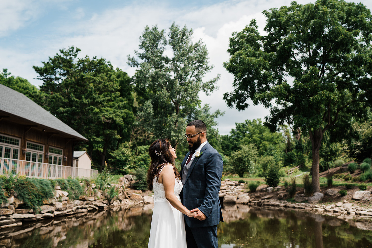 Bride and groom portrait in front of the rustic stone pond and Grand Lodge at Glasbern Inn in Fogelsville, PA.