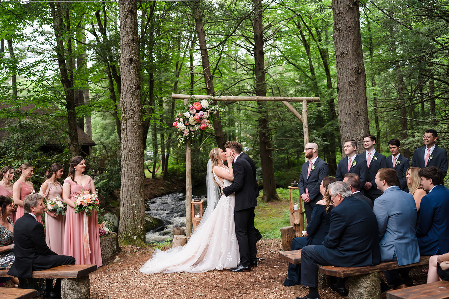 Newlyweds kissing during a streamside forest wedding ceremony at Magnolia Streamside Resort in the Poconos.