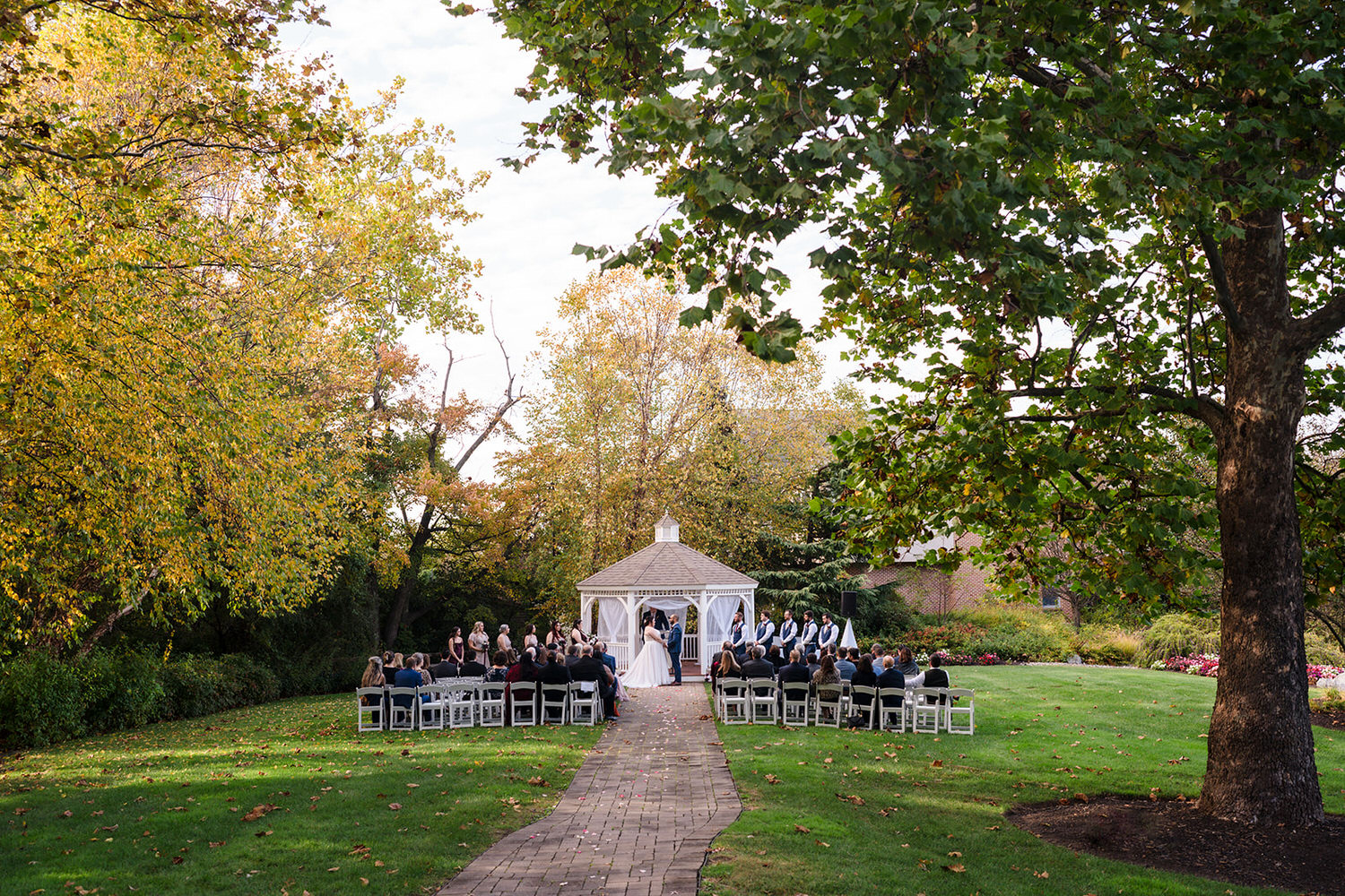 Outdoor wedding ceremony at a white gazebo surrounded by colorful fall foliage at Spring Mill Manor in Bucks County.