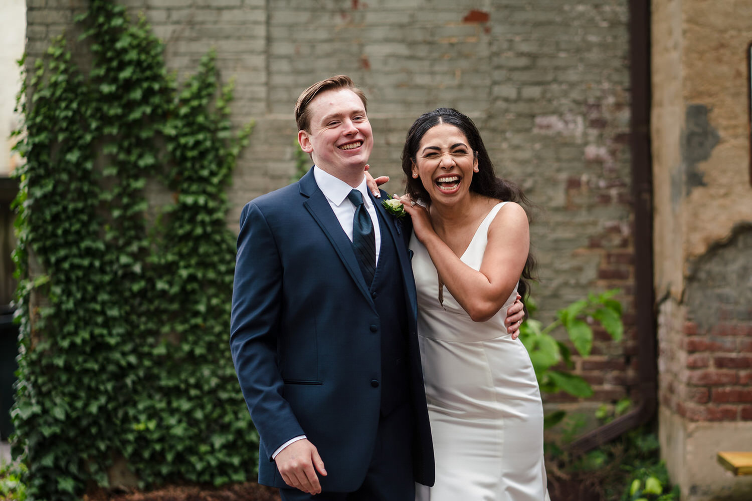 Candid laughter from a bride and groom in the historic ivy-covered courtyard at Tavern at the Sun Inn in Bethlehem, PA.