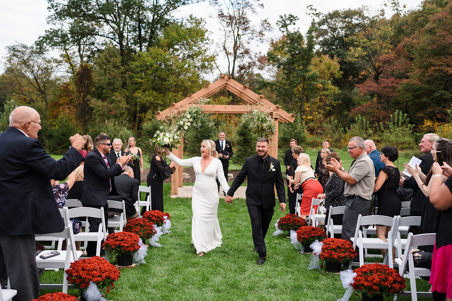 Newlyweds walking through a cheering crowd during a farm wedding ceremony at The Barn at Gravers Tree Farm in Schuylkill County.