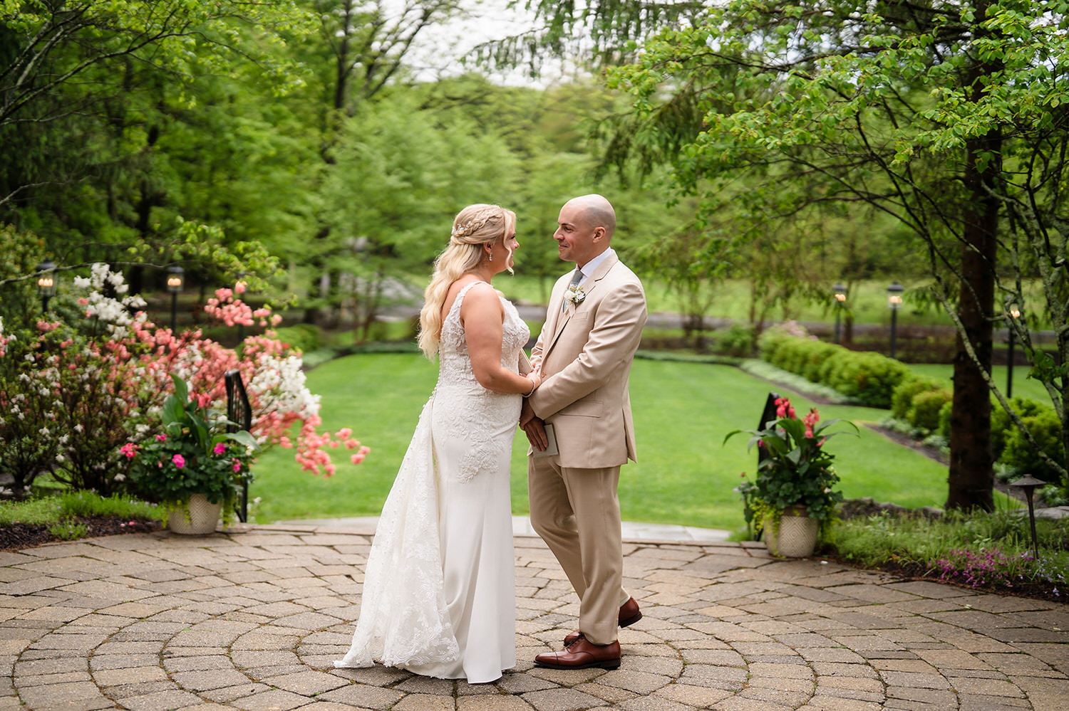 Newlyweds holding hands in the manicured gardens at The Lodge at Mountain Springs Lake forest retreat in the Poconos.