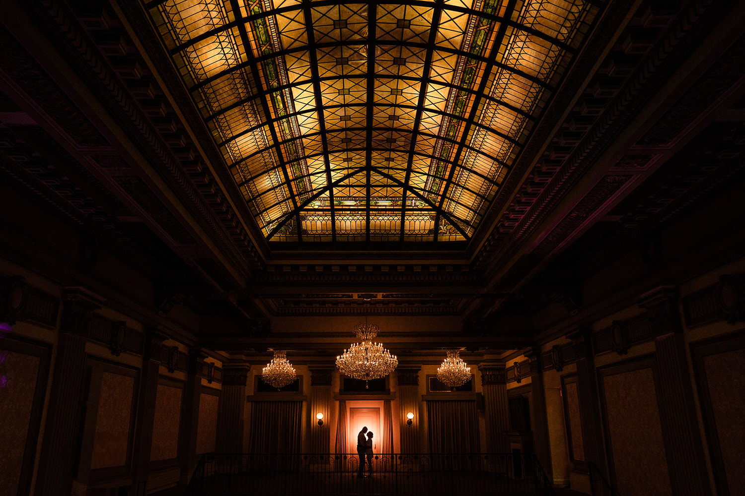 Newlyweds silhouetted under the iconic stained-glass ceiling and chandeliers at Vault 634 in Allentown, Lehigh Valley PA.