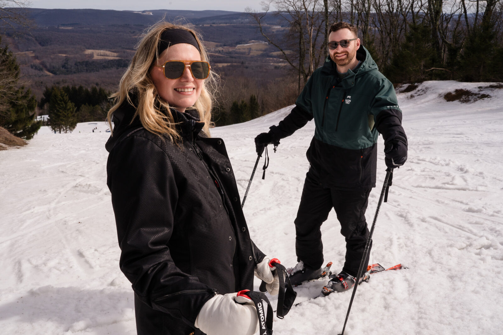 Couple in ski gear smiling together on slope during engagement session