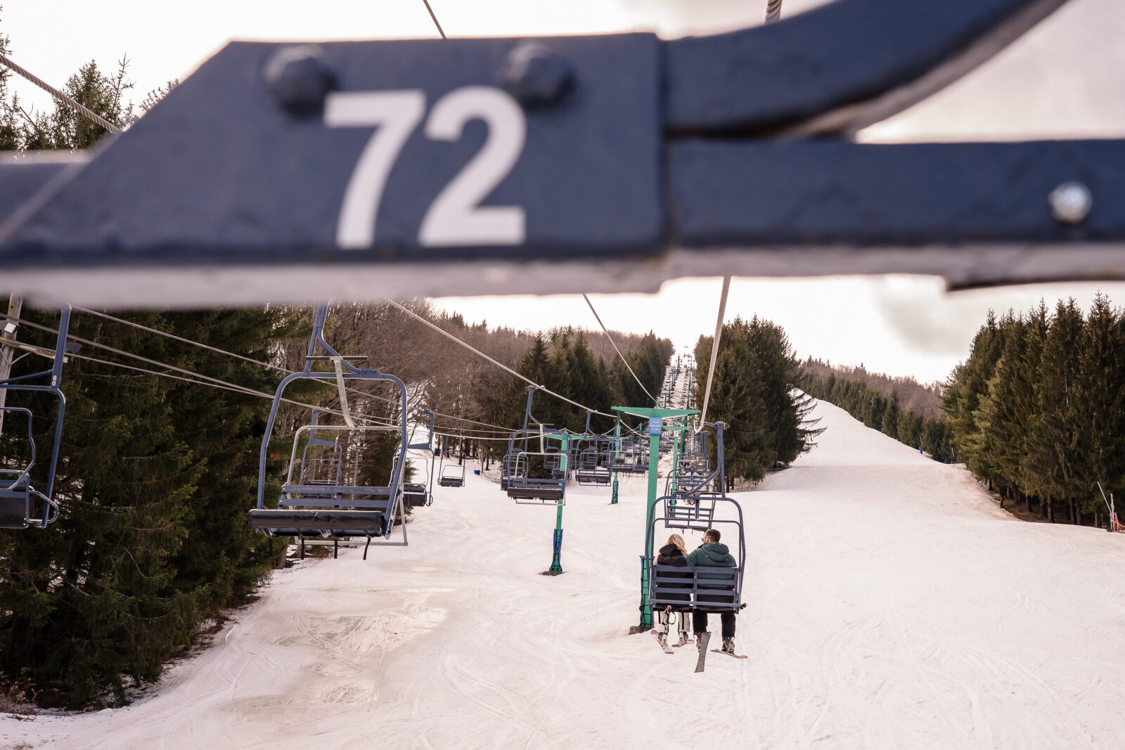 Close-up of ski lift number sign with chairs in snowy background