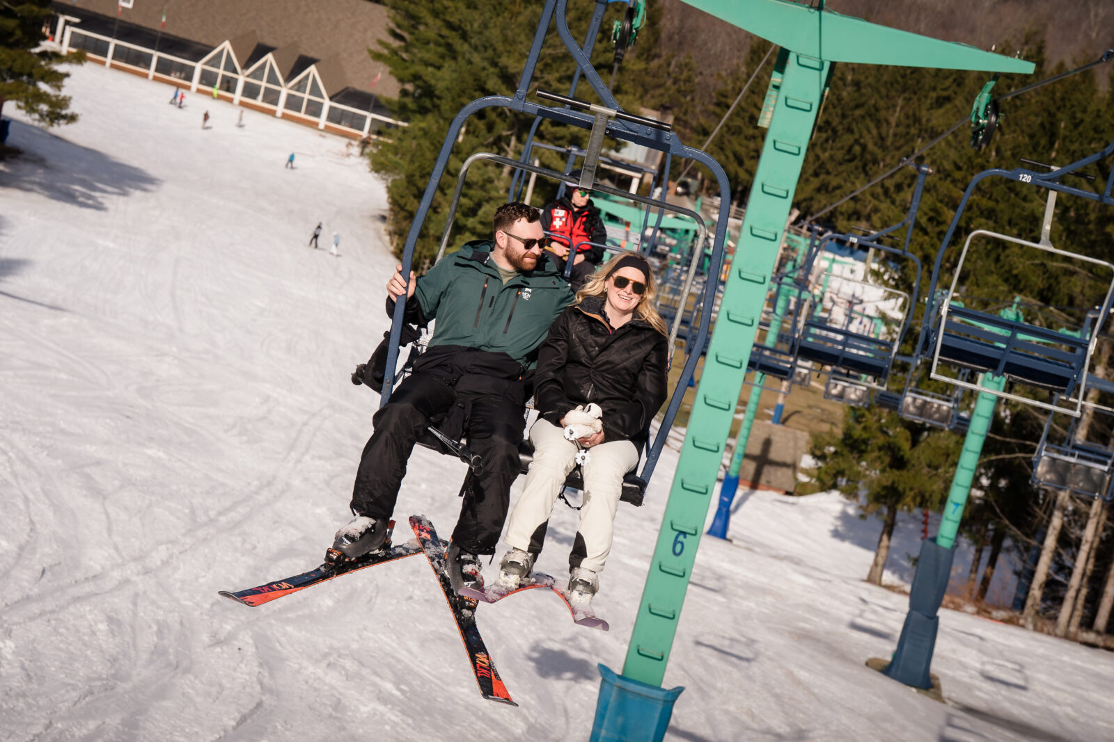 Couple riding ski lift together smiling during Elk Mountain engagement session