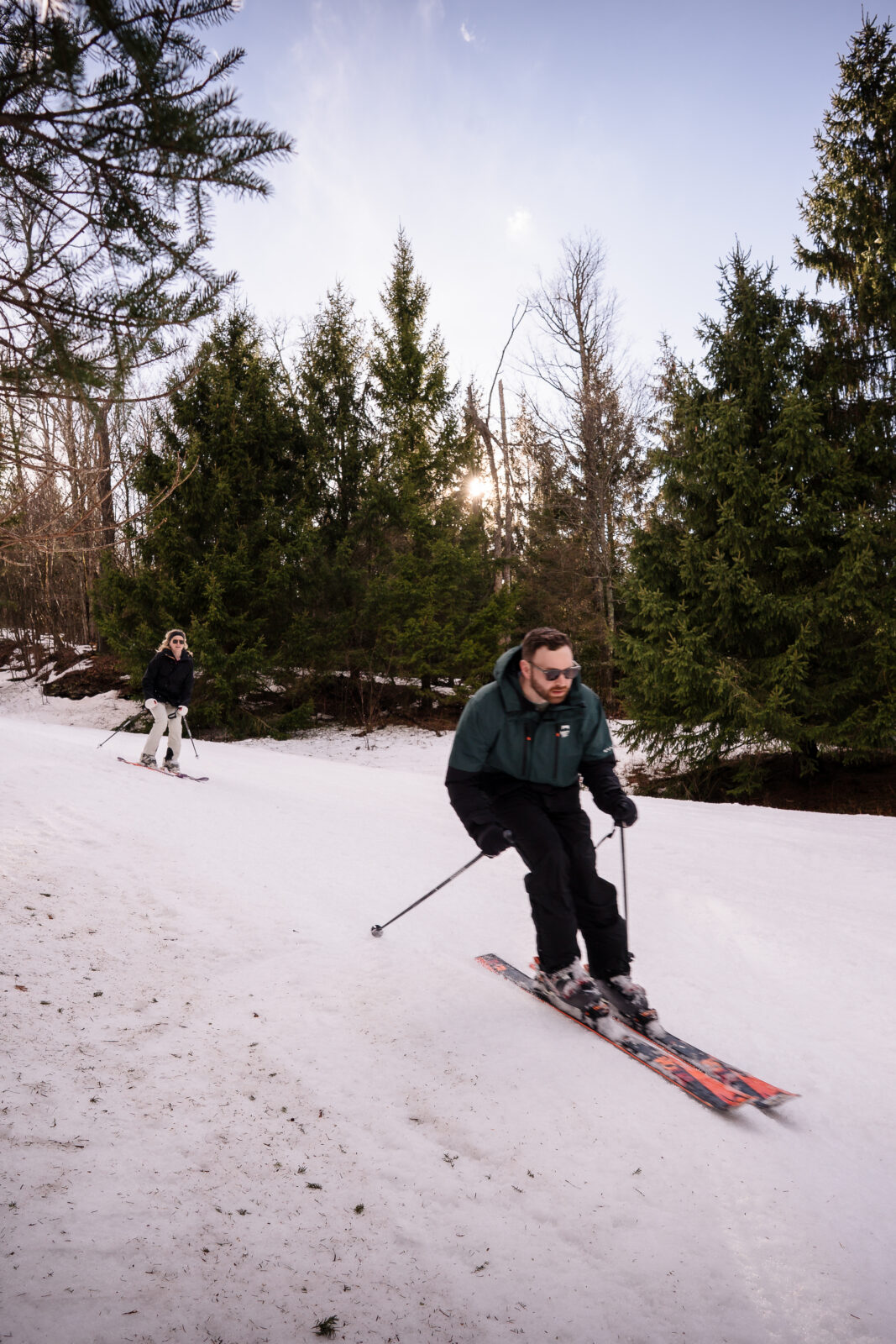 Groom skiing downhill during playful winter engagement session