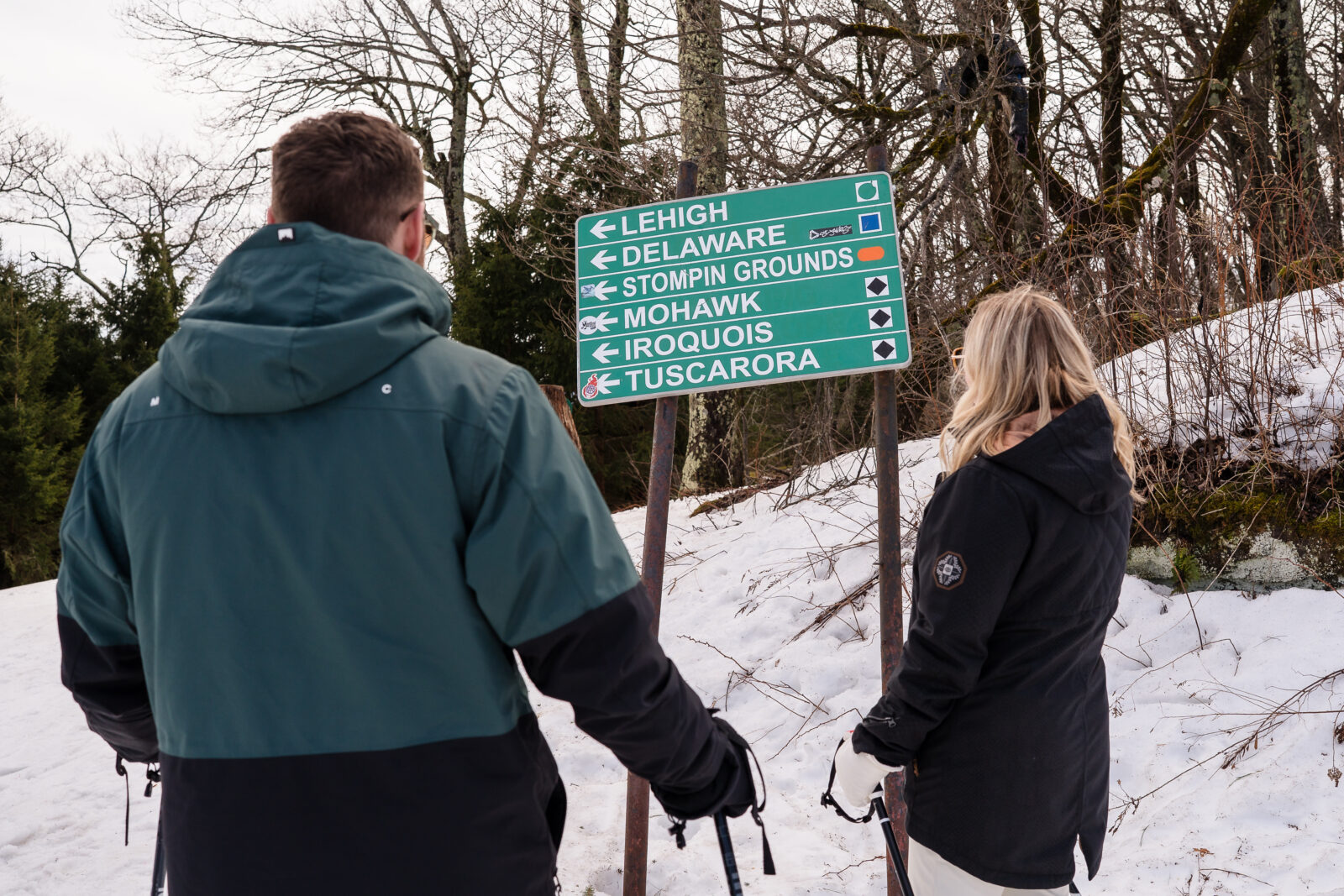 Couple skiing toward trail sign at Elk Mountain resort