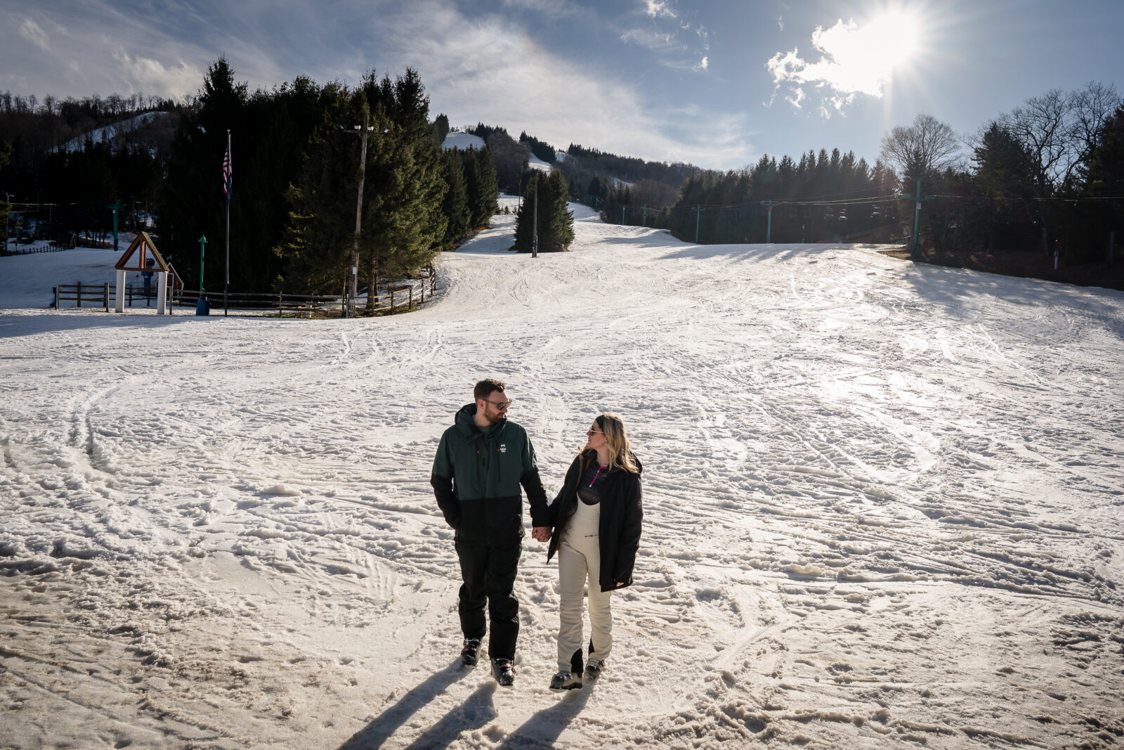 Engaged couple holding hands on ski slope with mountain views at Elk Mountain Resort