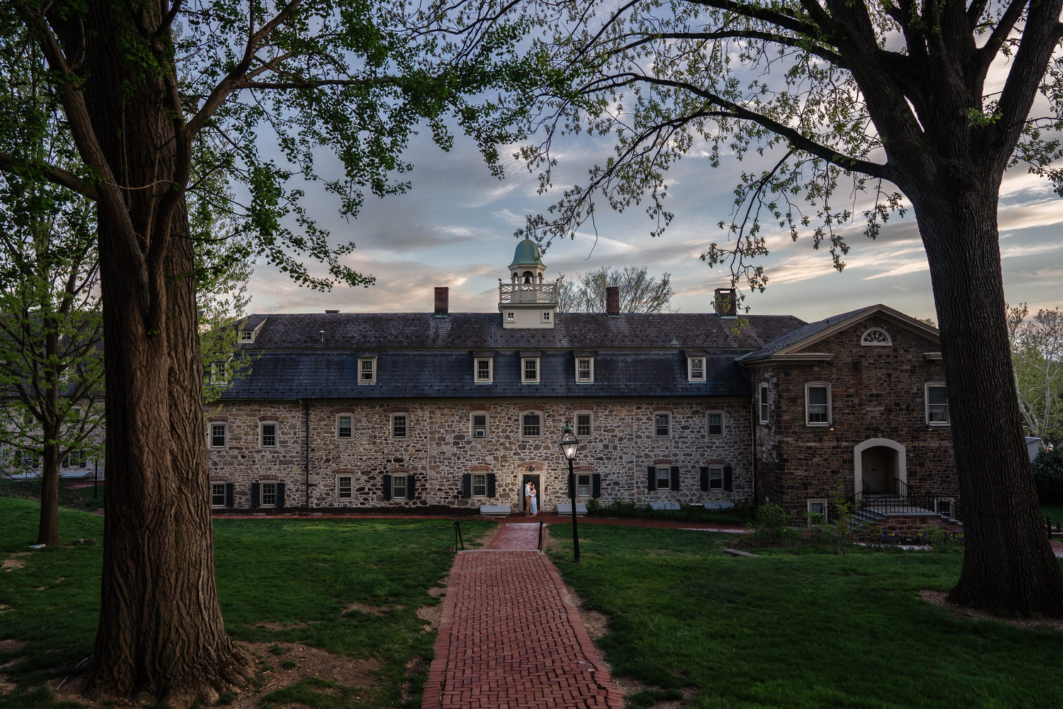 Wide environmental shot of a brick path leading toward a historic Moravian University building
