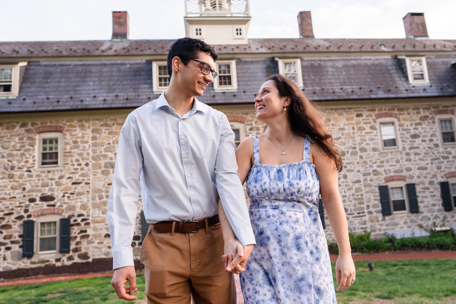 couple walking together smiling at one another in front of a historic Moravian University Building