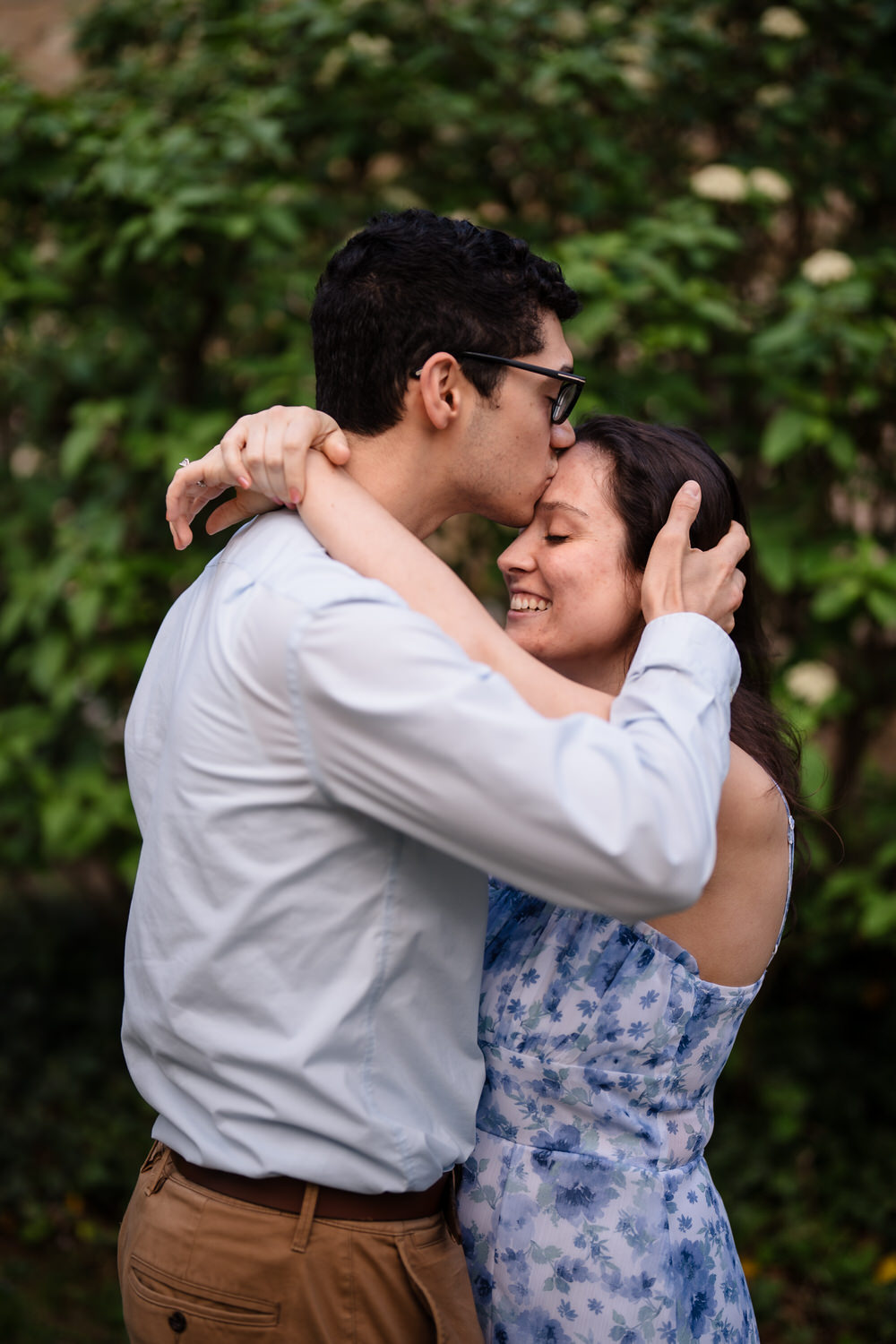 couple kisses in front of an ivy wall