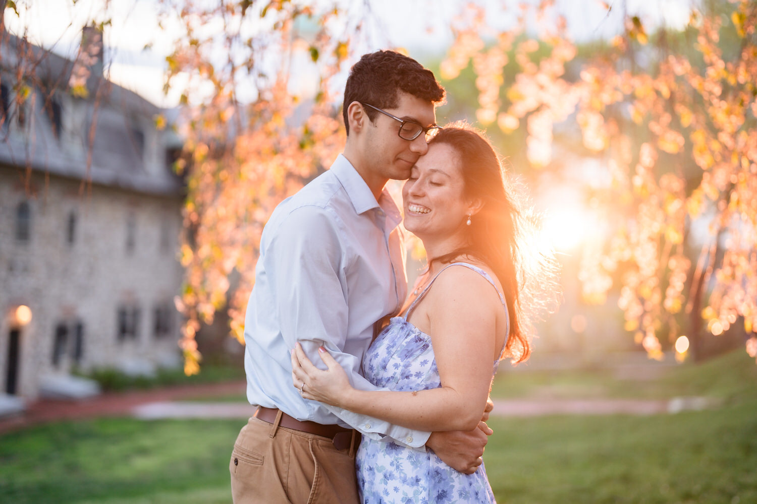 Couple embraces with strong golden hour sunburst behind them
