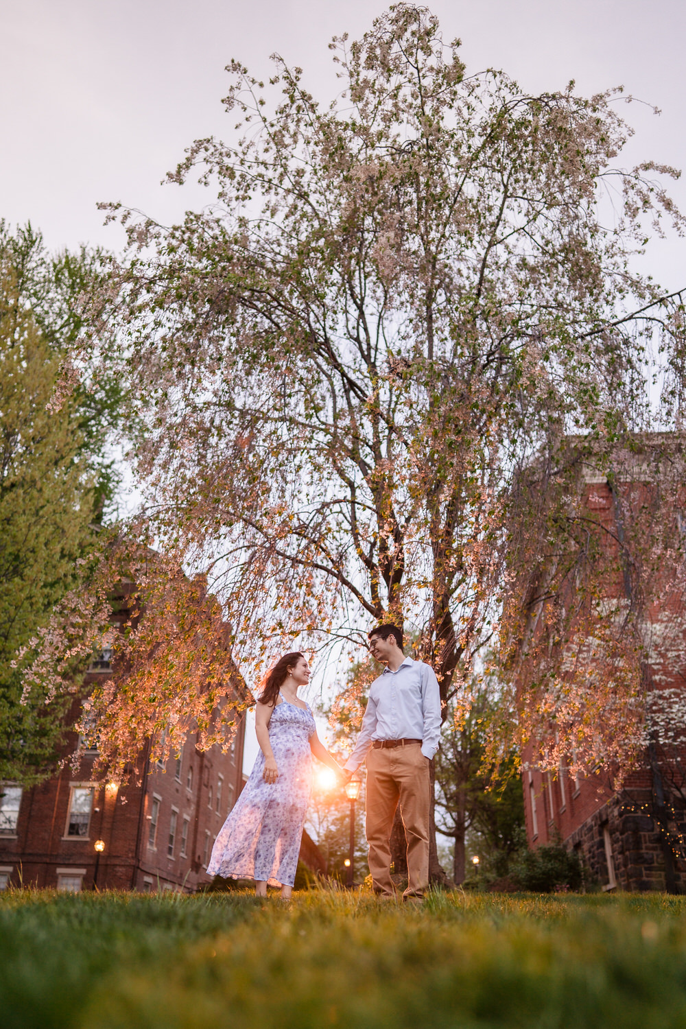 Couple poses among full spring foliage at golden hour