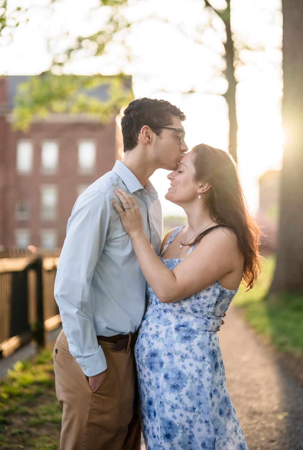Man kisses fiancée on the forehead with sunset behind him at God's Acre, Bethlehem PA
