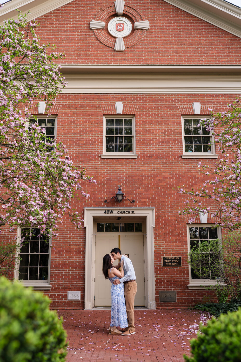 Couple poses at the brick building entrance of a historic Moravian University building, Bethlehem PA

